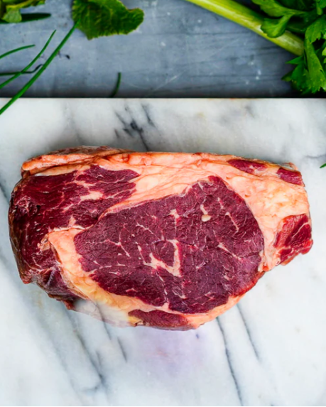 Raw steak on a marble surface with herbs